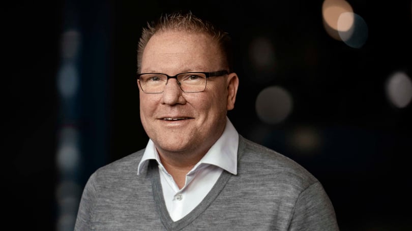 Porträtt av en man i vit skjorta och grå tröja