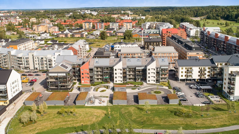 Flygvy över ett bostadsområde med flerfamiljshus, innergårdar, parkeringsplatser och grönområden