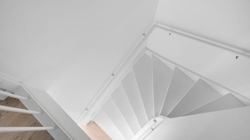 Inflyttningsklart trapphus med vit spiraltrappa och ljusa väggar