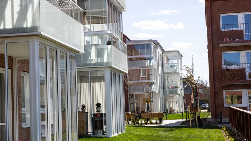 Inflyttningsklar lägenhet i modernt bostadshus med glasade balkonger och grön innergård