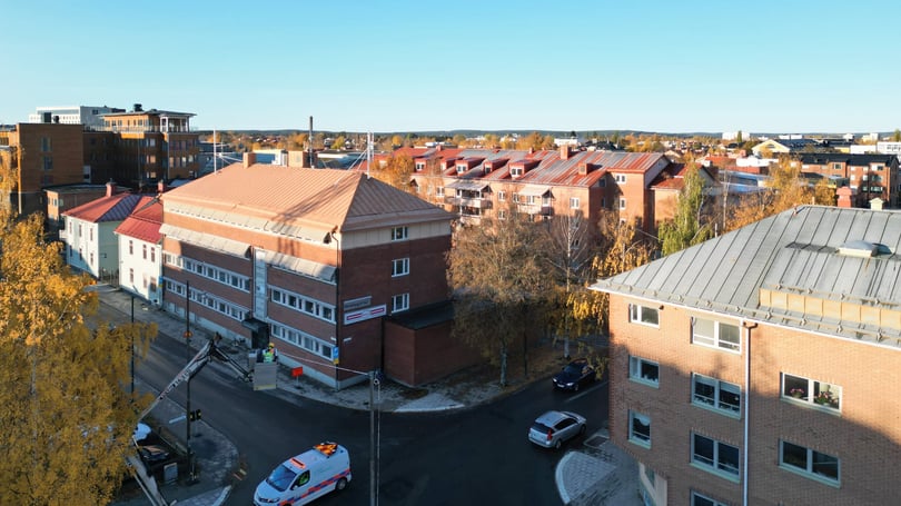Flygvy över bostadskvarter med flerfamiljshus, träd och höstfärger