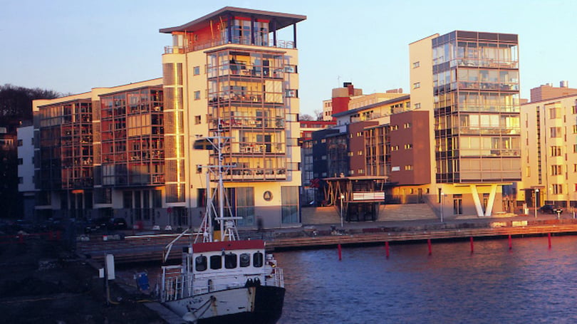Bostadshus vid vattnet i kvällsljus med en båt i förgrunden