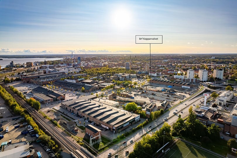 Flygvy över en stad med byggnader, gröna områden och markerad plats för Brf Kopparvalvet