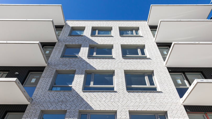 Flerbostadshus med vita balkonger och fönster i fasad