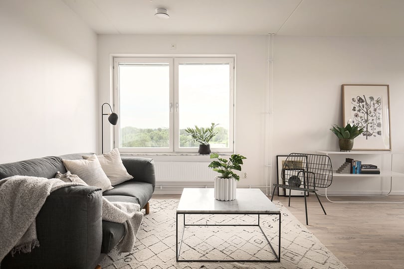 Inflyttningsklart vardagsrum med soffa, soffbord, fönster och ljusa väggar