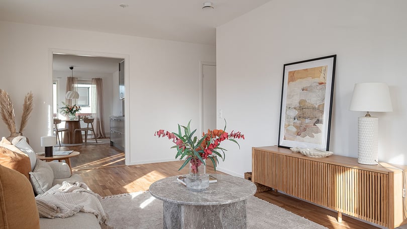 Inrett vardagsrum med soffa, soffbord, sideboard och konst på väggen, med utsikt mot matplatsen