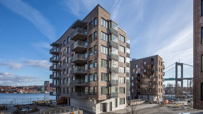 Modernt bostadshus vid vattnet med balkonger och utsikt över en bro