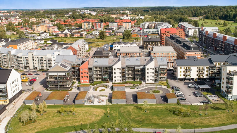 Flygvy över ett bostadsområde med flerfamiljshus, innergårdar, parkeringsplatser och grönområden