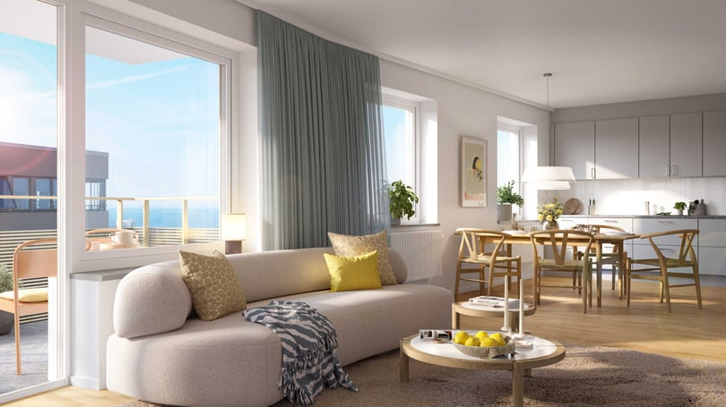 Lägenhet med öppen planlösning, ljus soffa, matplats och kök med stora fönster mot havet