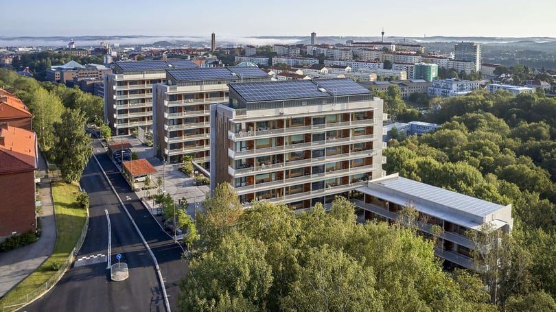 Bostadsområde med moderna flerfamiljshus med solpaneler och grönska i förgrunden