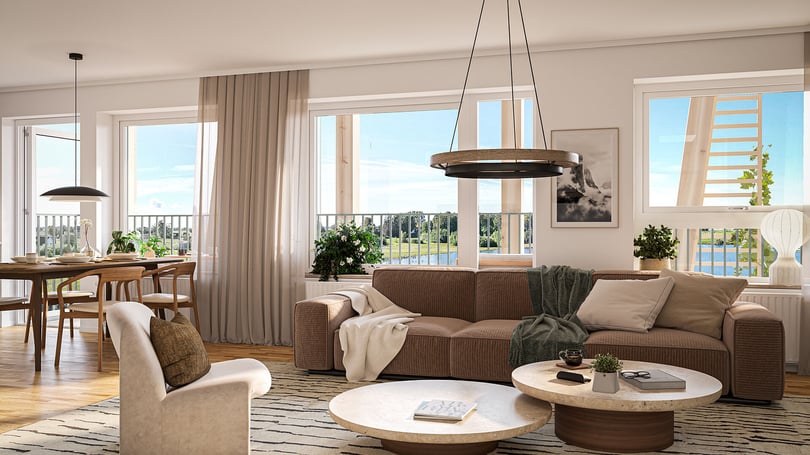 Ljust vardagsrum med brun soffa, fåtölj, matplats och stora fönster mot utsikt över vatten