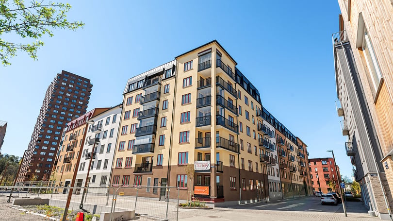 Nybyggda flerbostadshus med balkonger i ett modernt bostadsområde under klarblå himmel