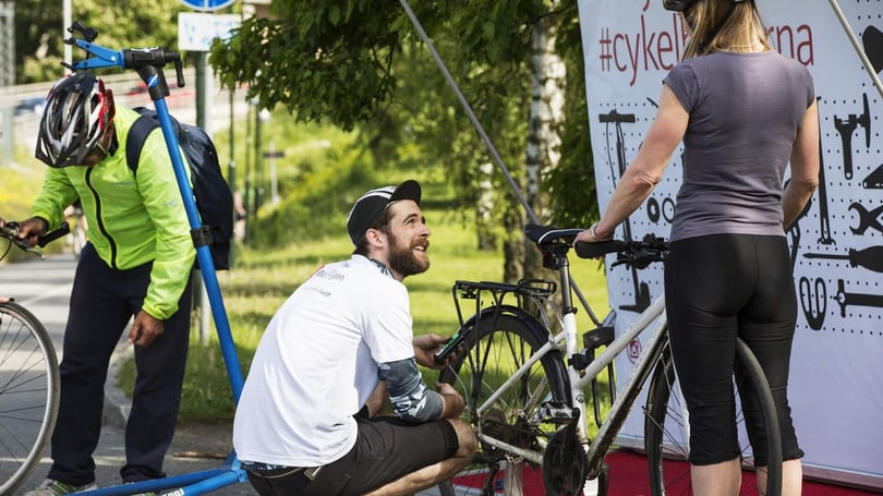 Tre personer fixar med cyklar vid en cykelverkstad