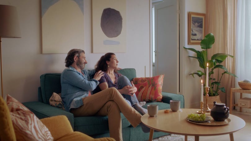 Två personer sitter i en soffa i ett ombonat vardagsrum