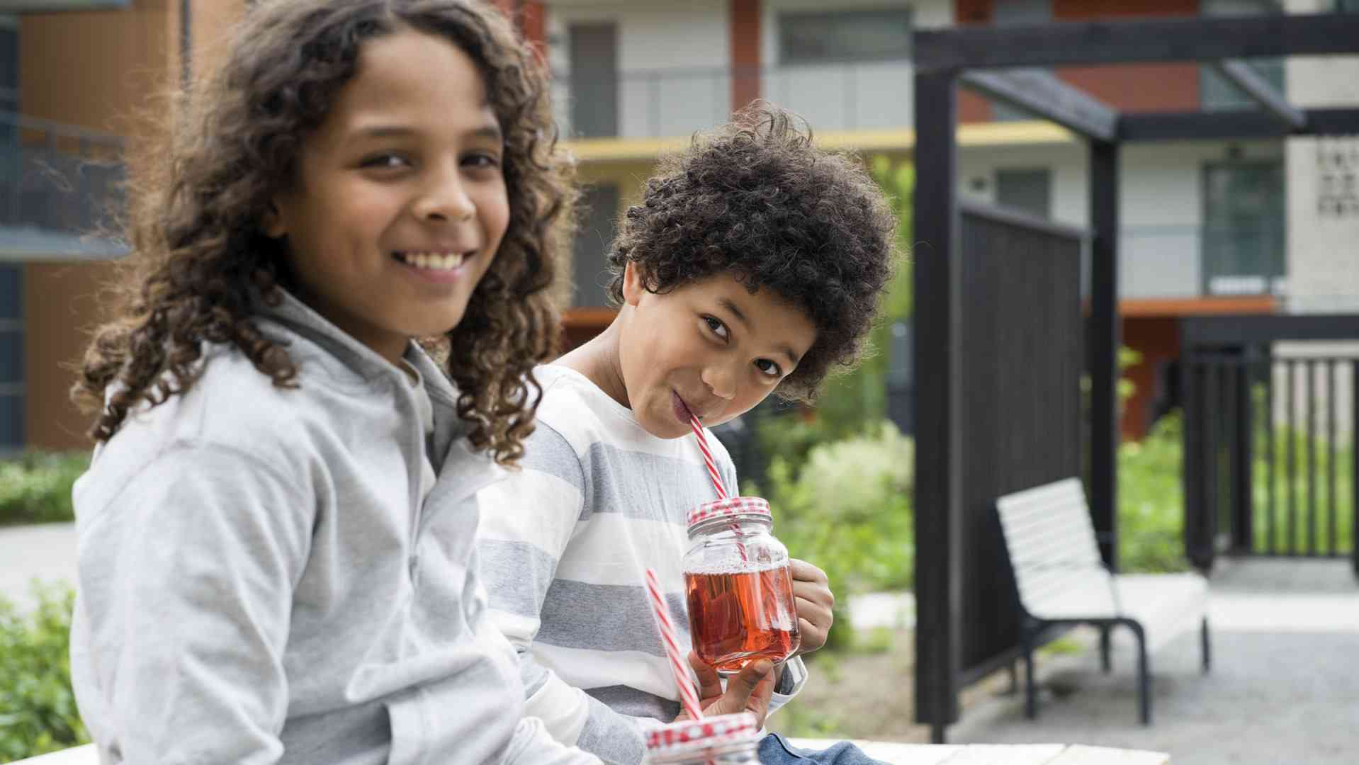 Barn dricker saft ur burk på innergård