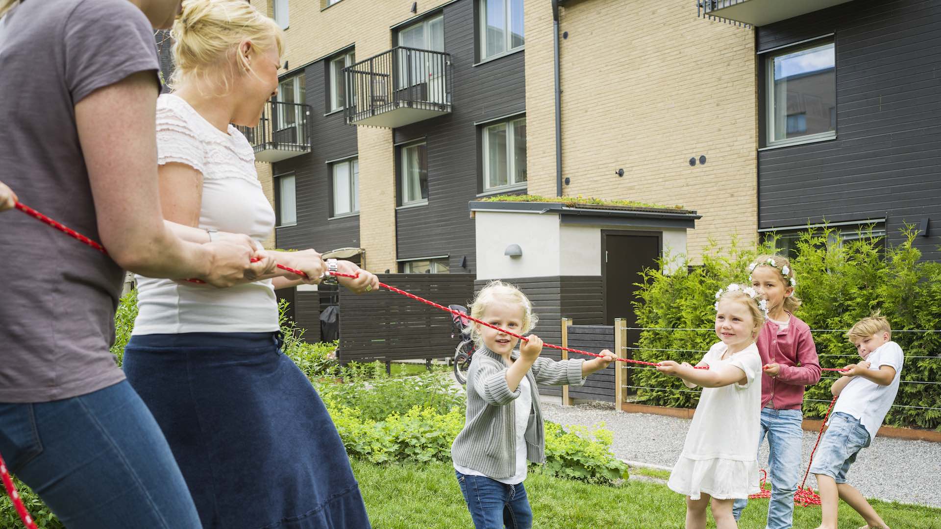 Barn och vuxna i dragkamp på innergård