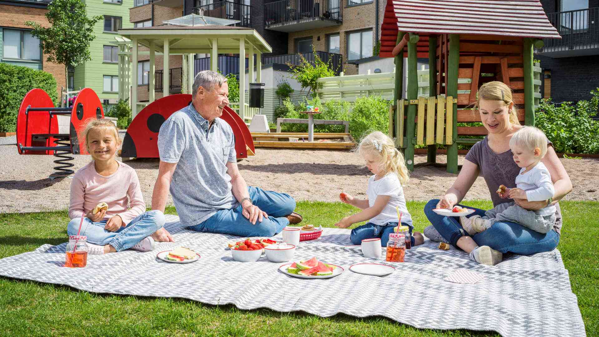 Barn och vuxna på picknickfilt på innergård