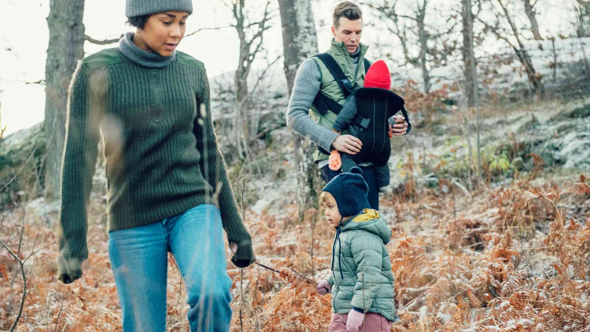 Två vuxna och två små barn på skogspromenad