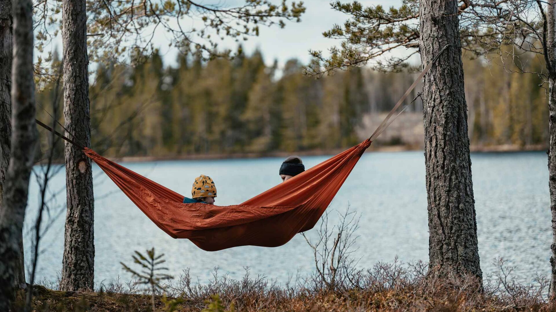 Vuxen och barn i hängmatta vid vatten