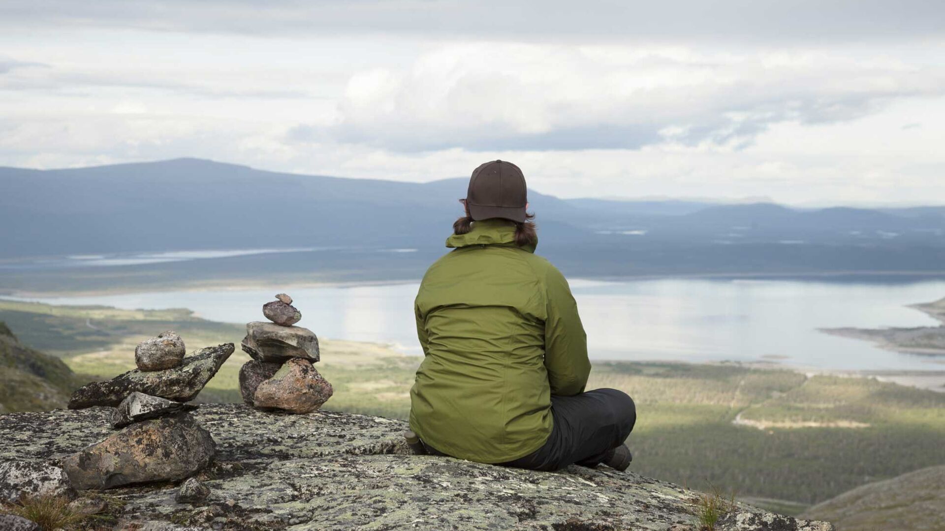 Kvinna som sitter och tittar ut över fjällvärlden 