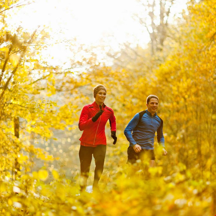 Par som joggar i skogen på hösten
