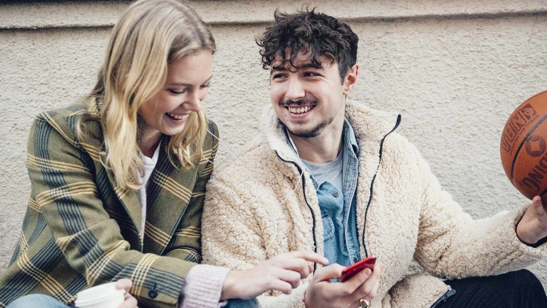 Ung kvinna och man tittar på telefon